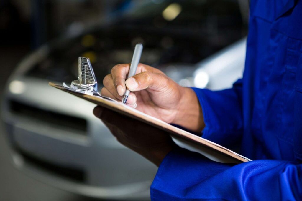 Kfz-Sachverständiger dokumentiert Fahrzeugdaten vor geöffneter Motorhaube