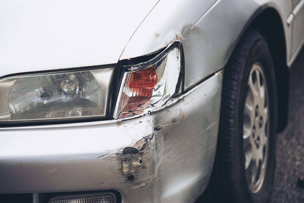 Beschädigter Kotflügel und gebrochener Blinker an einem silbernen Fahrzeug