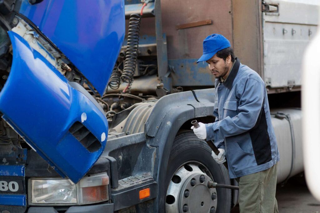 Mechaniker arbeitet an einem blauen Lkw mit hochgeklapptem Fahrerhaus